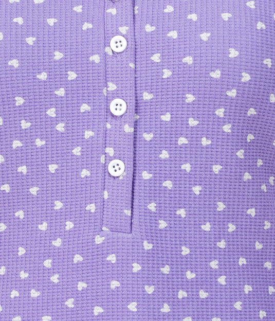 Close-up of a purple textured fabric with white heart patterns and buttons.