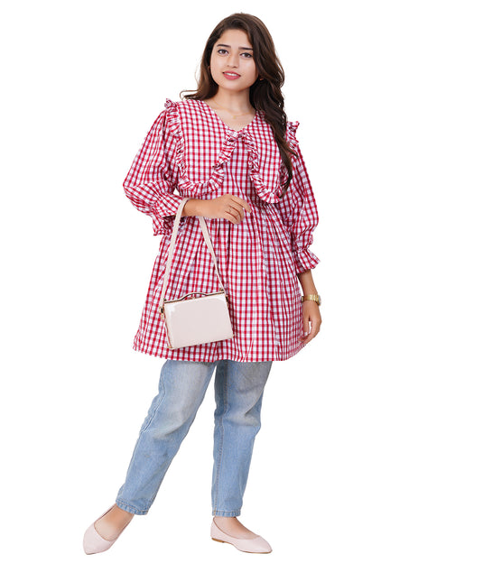Woman wearing a red and white checkered dress with light blue jeans on a white background