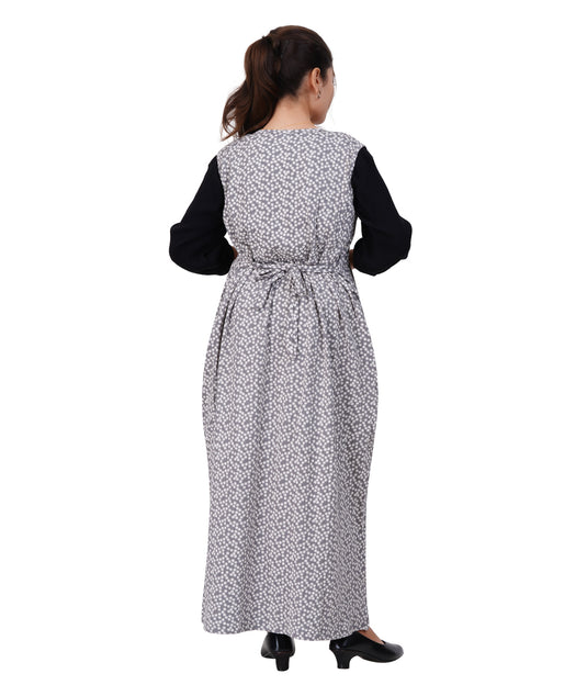 Woman wearing a long, patterned dress with a black top on a white background