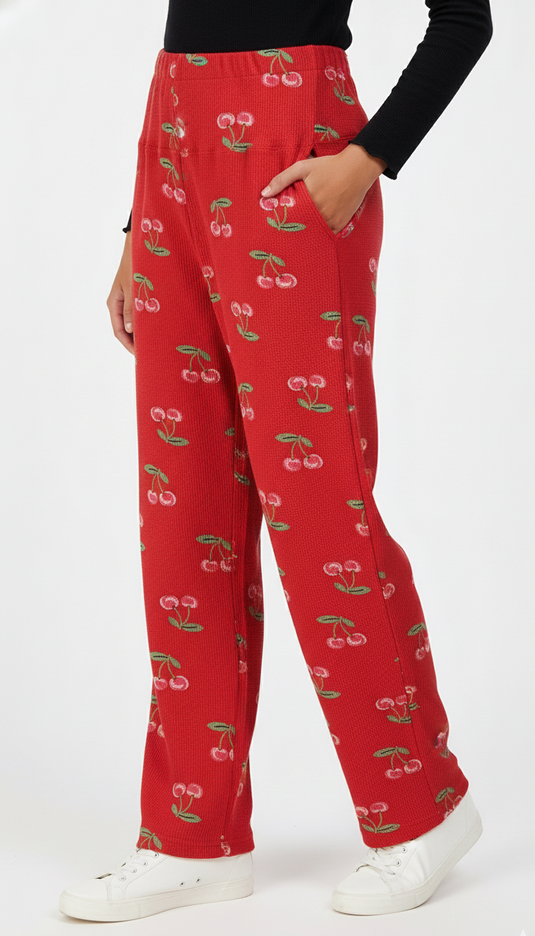 Red bump support pants with cherry pattern worn by a person on a white background