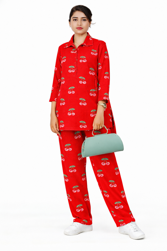Woman wearing a red outfit with a cherry fruit pattern, holding a green handbag on a white background