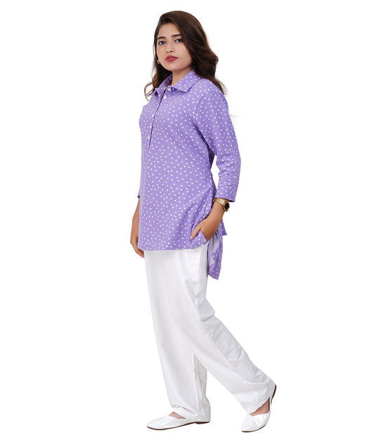Woman wearing a purple polka dot shirt and white pants on a white background