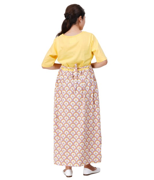 Woman wearing a yellow top and patterned skirt on a white background