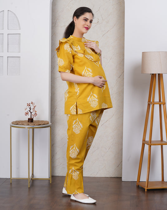 Pregnant Woman with bump wearing a yellow maternity set outfit with white patterns in a minimalistic room.